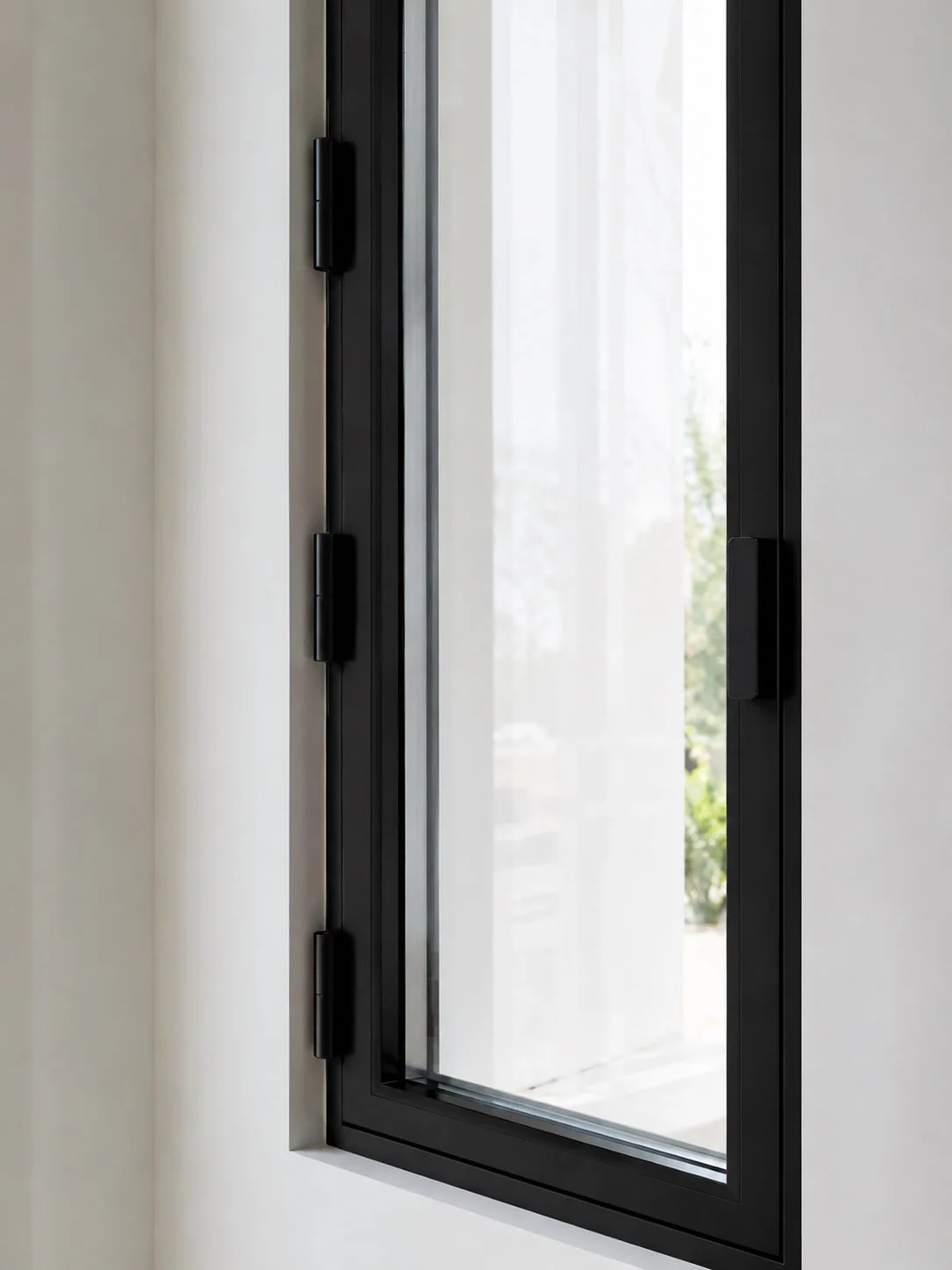Close-up detail of casement window hinges and aluminum frame